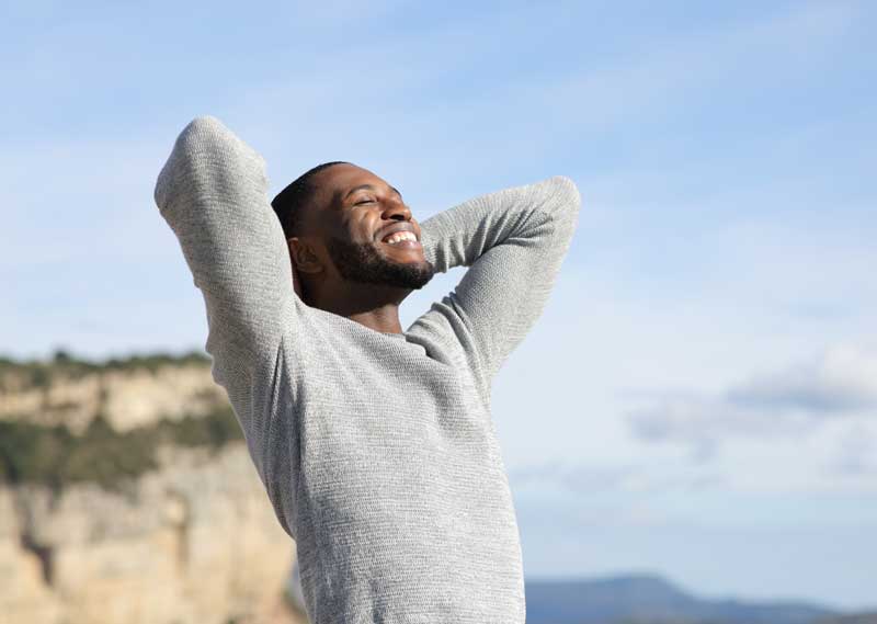 Relaxed man with black skin breathing in the mountain