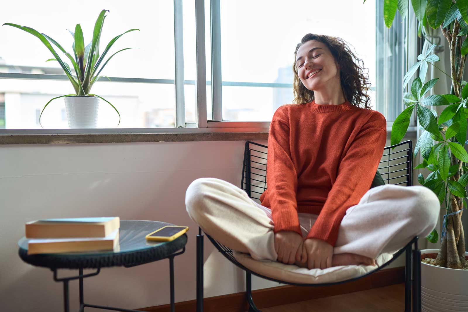 Young relaxed smiling pretty woman enjoying relaxing sitting on chair at home.
